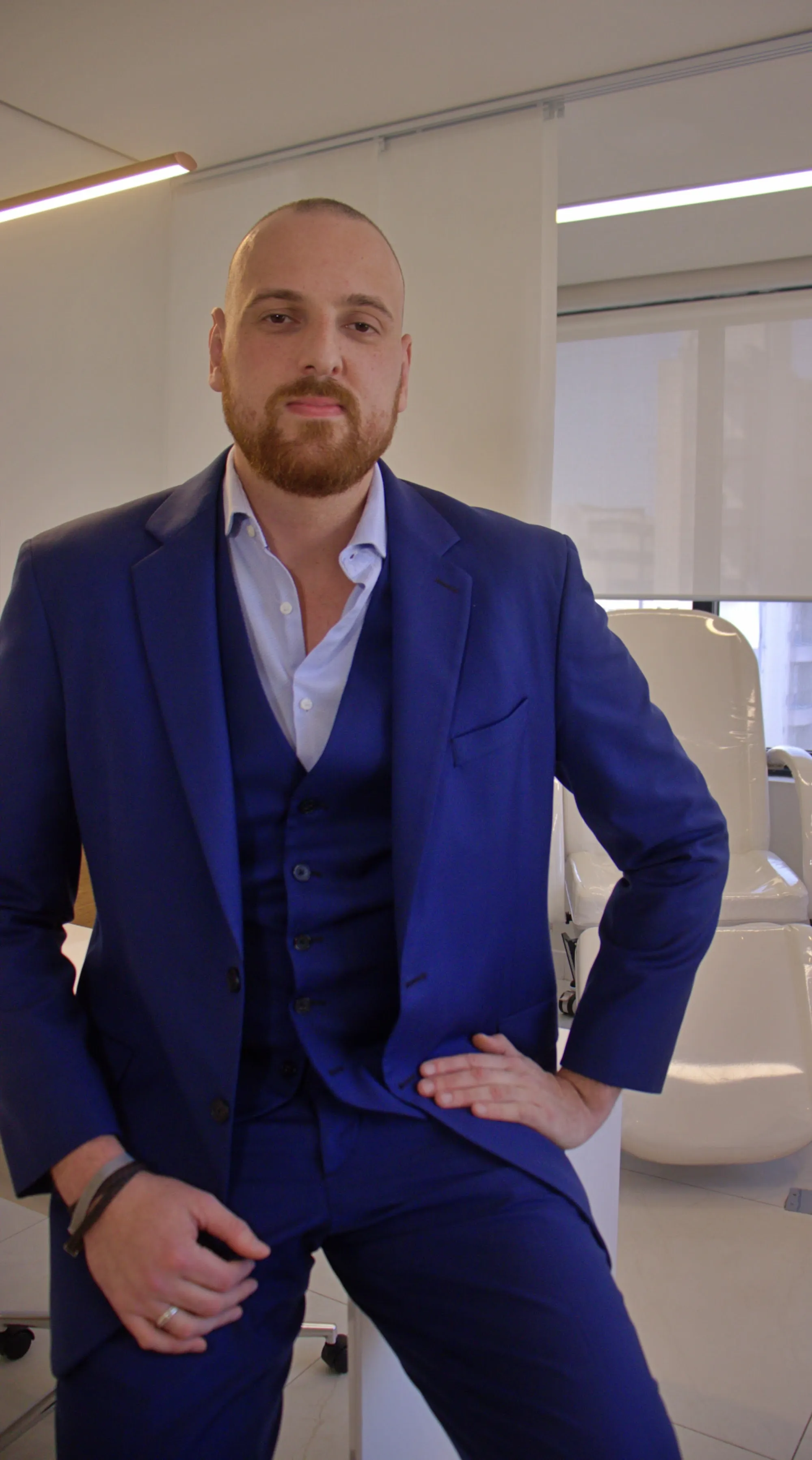 Dr. Guilherme Leitner, de terno azul, apoiado na mesa do consultório